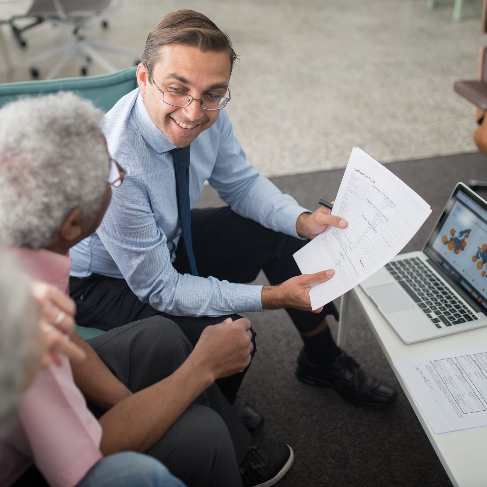 An advisor sitting with an older couple, talking them through an application form before anything is signed.