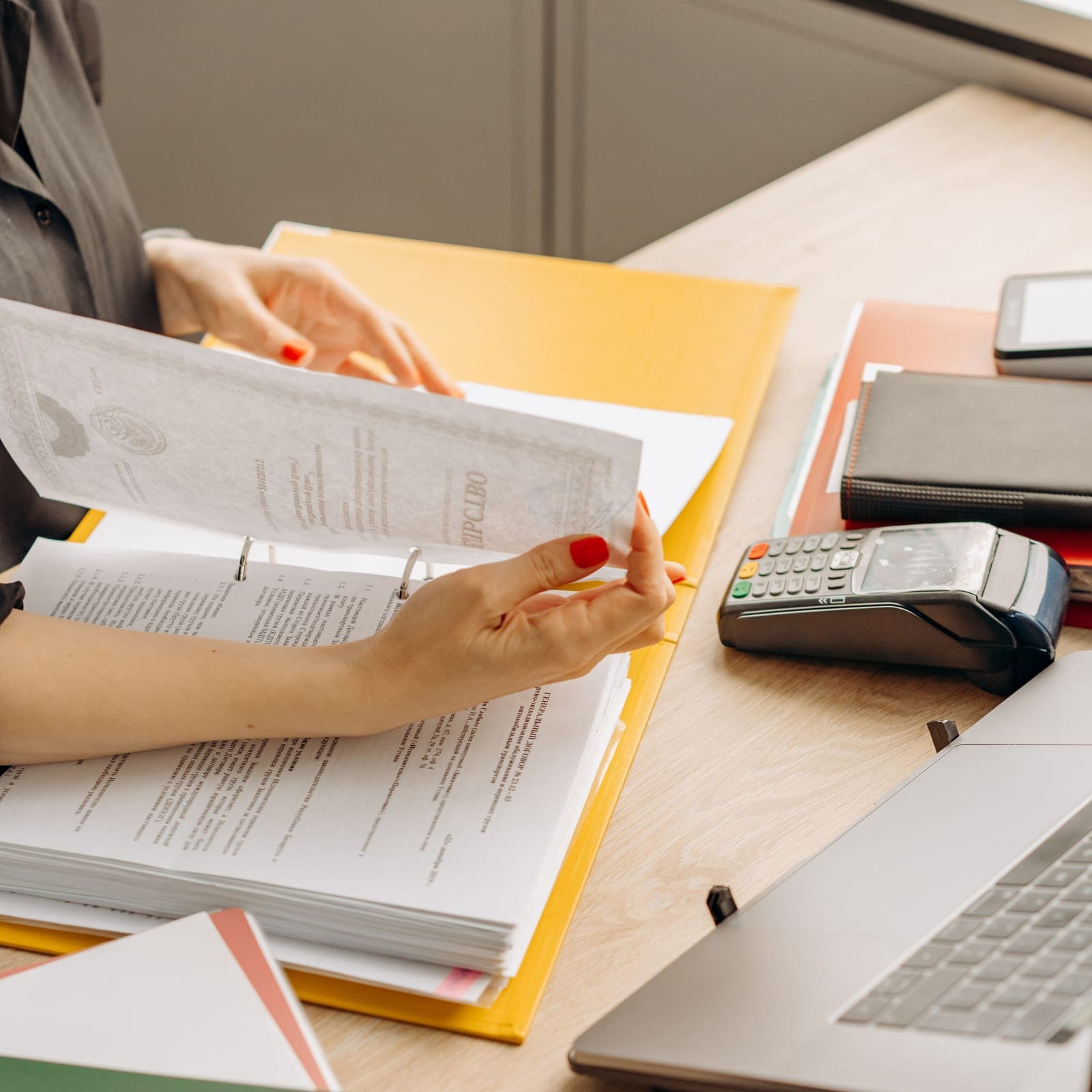 Two sets of hands comparing printed policy documents side by side on a desk.